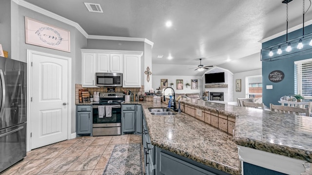 kitchen featuring visible vents, a peninsula, stainless steel appliances, a fireplace, and white cabinetry