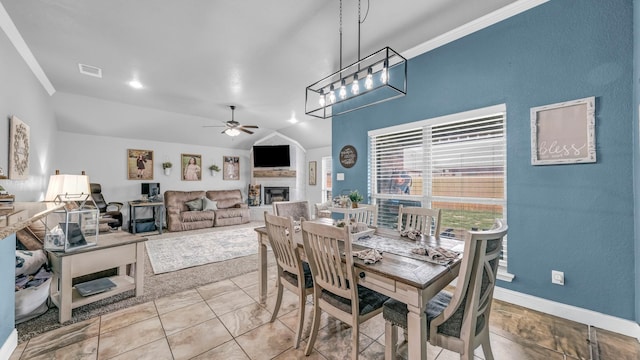 dining space with a fireplace, visible vents, a ceiling fan, vaulted ceiling, and baseboards