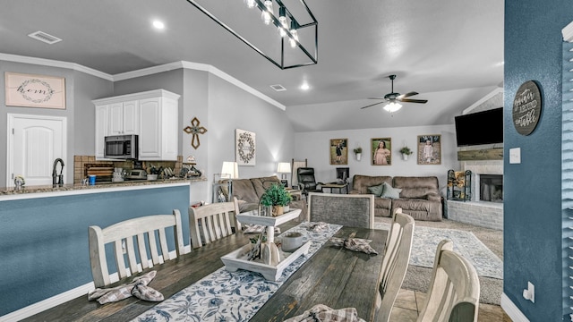 dining area featuring ornamental molding, vaulted ceiling, visible vents, and a fireplace