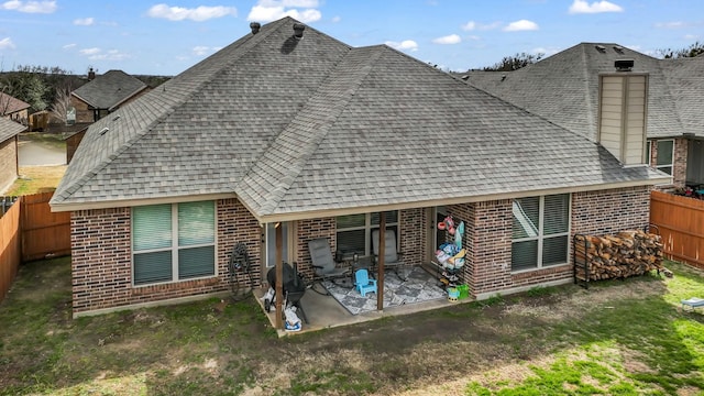 back of property with a patio area, a shingled roof, a fenced backyard, and brick siding