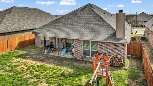 back of property with a patio, a fenced backyard, central air condition unit, a shingled roof, and brick siding