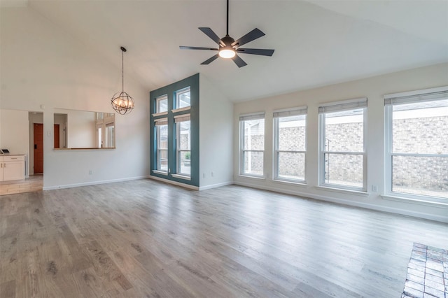 unfurnished living room featuring baseboards, high vaulted ceiling, light wood-style flooring, and ceiling fan with notable chandelier