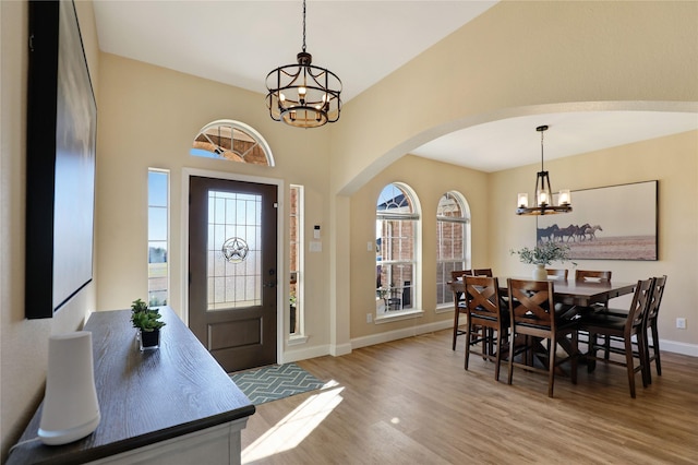 entryway with light wood finished floors, a wealth of natural light, and a notable chandelier