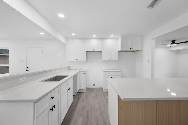 kitchen featuring white cabinets, ceiling fan, light wood-type flooring, a sink, and recessed lighting