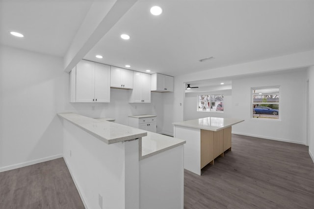 kitchen with dark wood-type flooring, recessed lighting, white cabinets, and a kitchen island