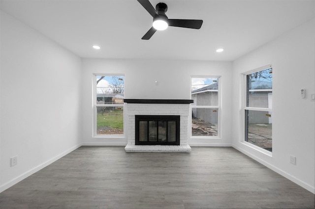 unfurnished living room featuring a brick fireplace, baseboards, wood finished floors, and recessed lighting