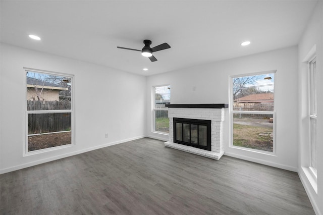 unfurnished living room featuring recessed lighting, a brick fireplace, dark wood finished floors, and baseboards