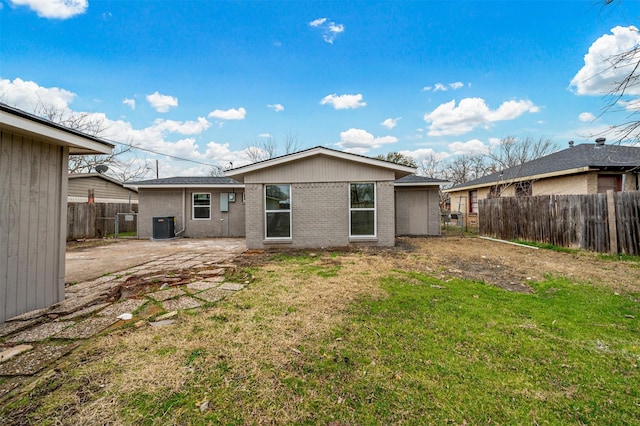 rear view of property featuring brick siding, a lawn, a patio area, fence, and cooling unit