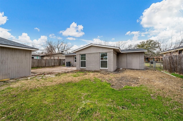 back of property featuring a patio, a fenced backyard, a yard, central AC, and brick siding