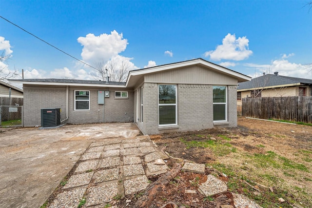 rear view of property with central AC, brick siding, a patio area, and fence