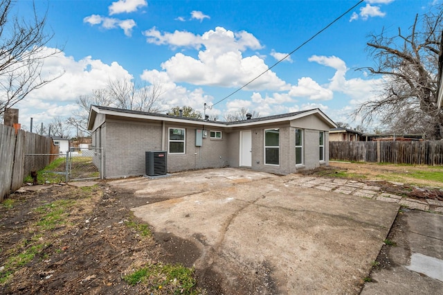 rear view of property featuring a patio area, brick siding, fence, and a gate