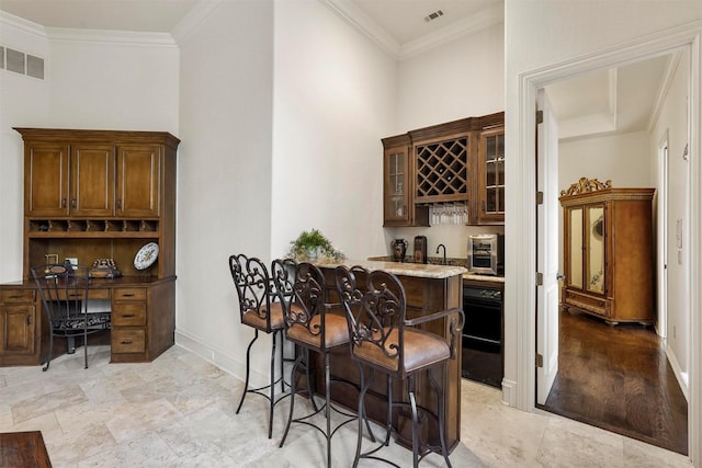 bar with visible vents, indoor wet bar, and ornamental molding