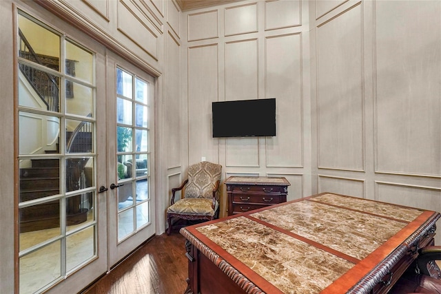 bedroom featuring french doors, dark wood-style flooring, and a decorative wall