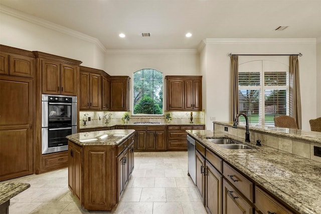 kitchen featuring light stone counters, stainless steel appliances, a sink, visible vents, and decorative backsplash