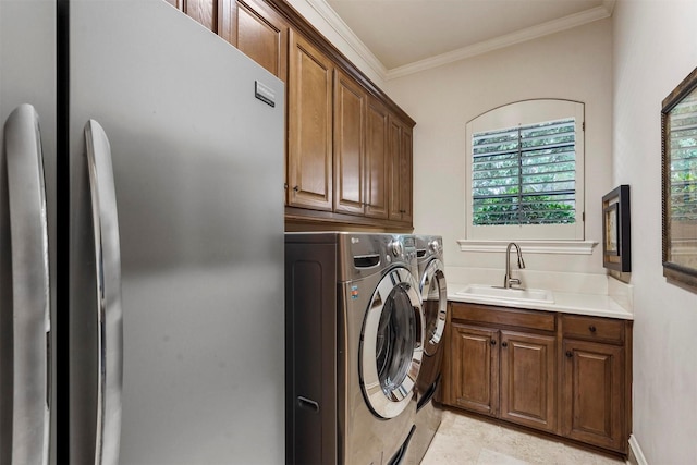 laundry area with cabinet space, crown molding, a sink, and washing machine and clothes dryer