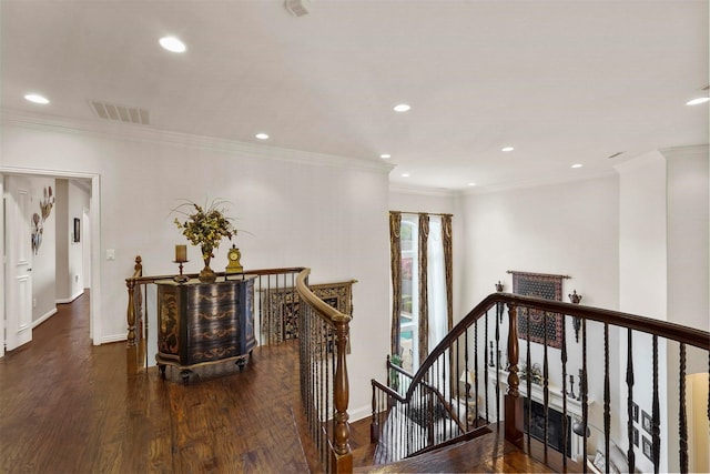 corridor with visible vents, ornamental molding, wood finished floors, and an upstairs landing