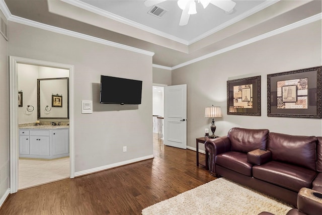 living area featuring a tray ceiling, wood finished floors, and visible vents