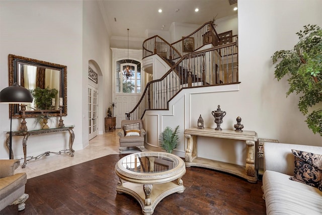 foyer entrance with ornamental molding, stairway, wood finished floors, and an inviting chandelier