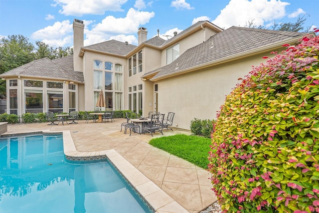 rear view of property featuring a patio area, an outdoor pool, and stucco siding