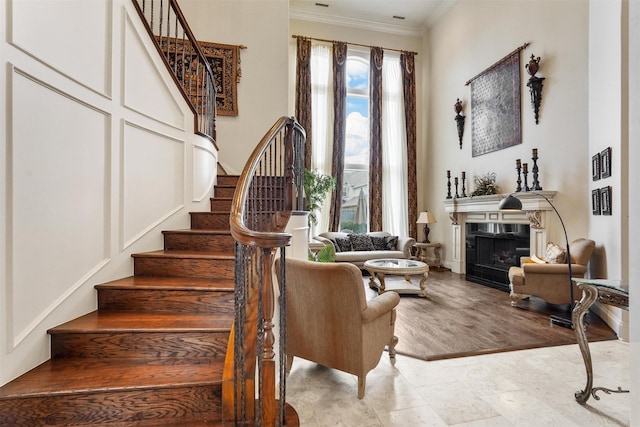 living area with ornamental molding, a fireplace, stairway, and light wood finished floors