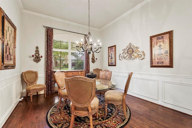 dining space featuring wainscoting, dark wood-type flooring, crown molding, a decorative wall, and a notable chandelier