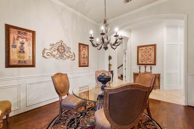 dining room featuring arched walkways, dark wood-type flooring, ornamental molding, and a decorative wall