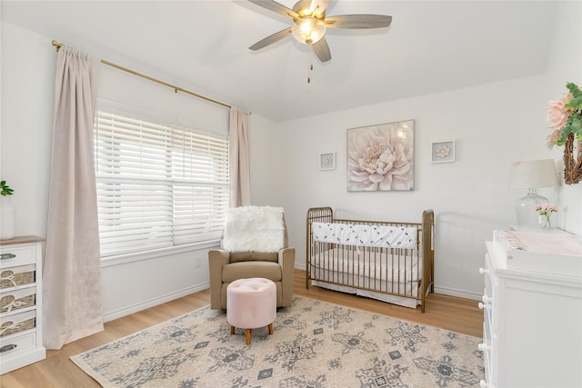 bedroom featuring a crib, light wood-type flooring, and baseboards