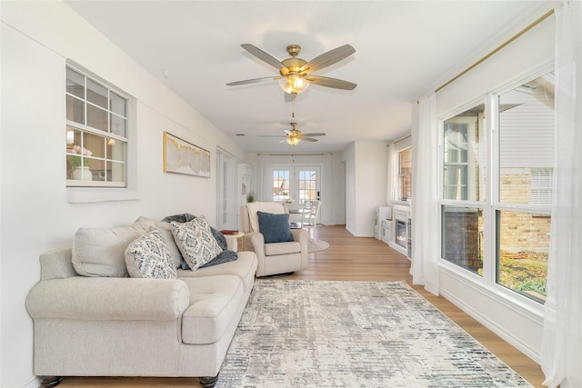 living area featuring a ceiling fan, baseboards, and wood finished floors