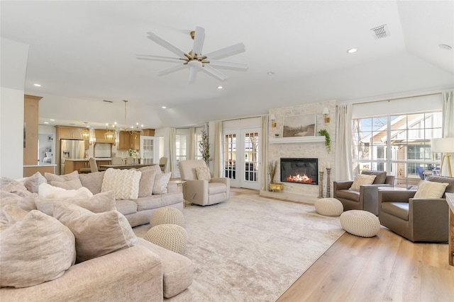 living area with light wood finished floors, a large fireplace, vaulted ceiling, and recessed lighting