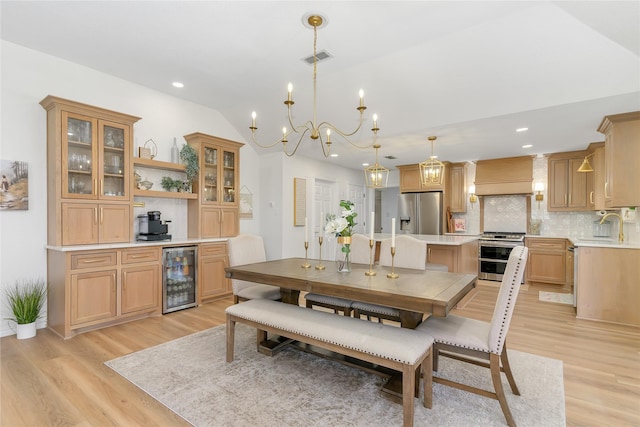 dining room featuring light wood-type flooring, wine cooler, visible vents, and lofted ceiling