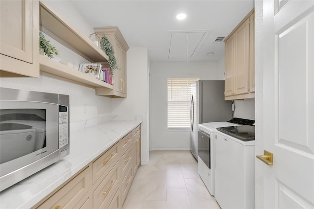 kitchen featuring cream cabinetry, light tile patterned floors, stainless steel microwave, visible vents, and washer and dryer