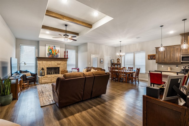 living area with a fireplace, dark wood finished floors, beamed ceiling, and ceiling fan with notable chandelier