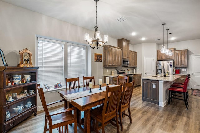 dining space with baseboards, visible vents, an inviting chandelier, and wood finished floors