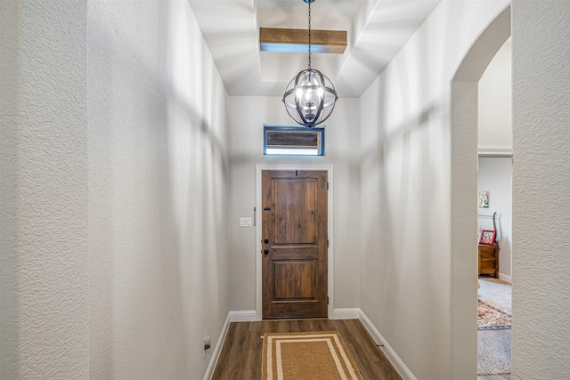 doorway featuring baseboards, arched walkways, dark wood-style flooring, beamed ceiling, and a notable chandelier