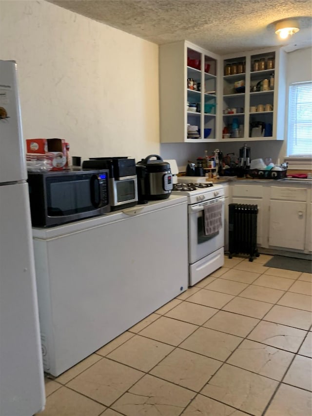 kitchen featuring white appliances, light tile patterned floors, open shelves, and a textured ceiling