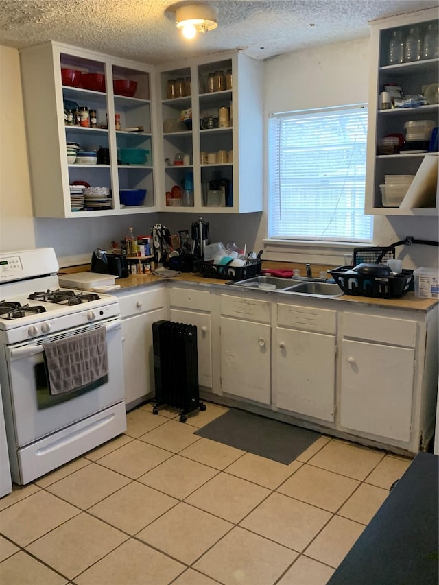 kitchen featuring white gas stove, open shelves, white cabinets, a sink, and a textured ceiling