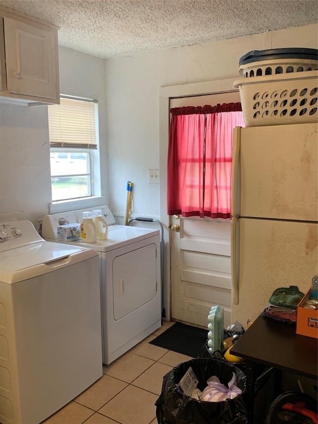 washroom featuring laundry area, a textured ceiling, washing machine and clothes dryer, and light tile patterned floors