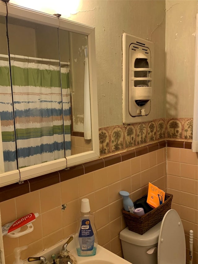 bathroom featuring toilet, a wainscoted wall, tile walls, and wallpapered walls