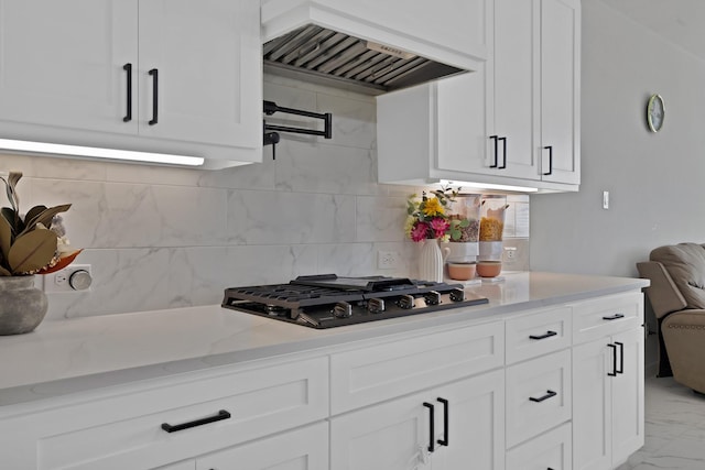 kitchen with white cabinets, light stone countertops, marble finish floor, custom exhaust hood, and gas cooktop