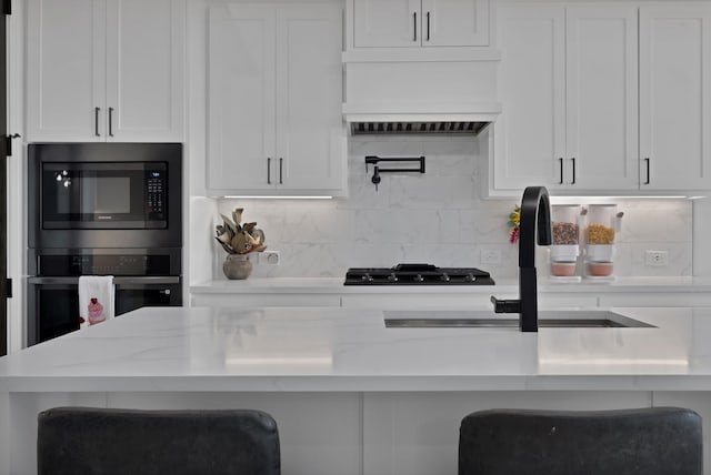 kitchen featuring decorative backsplash, white cabinetry, black gas stovetop, built in microwave, and oven