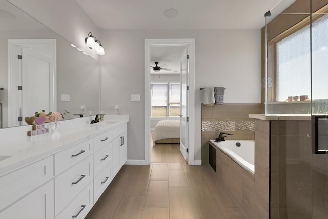 full bath with ensuite bathroom, ceiling fan, a sink, a bath, and double vanity