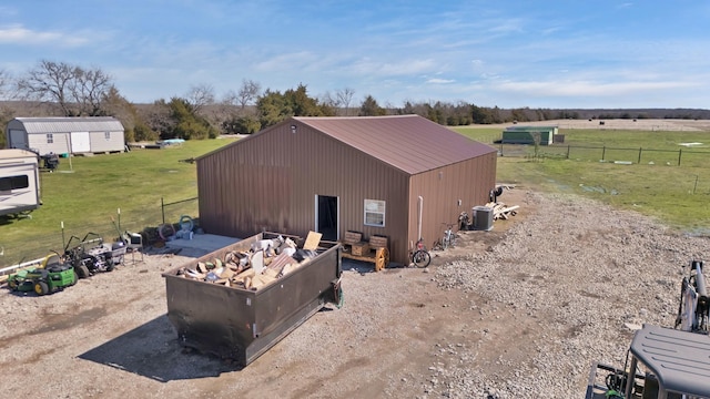 view of home's exterior featuring cooling unit, an outdoor structure, fence, a yard, and a pole building