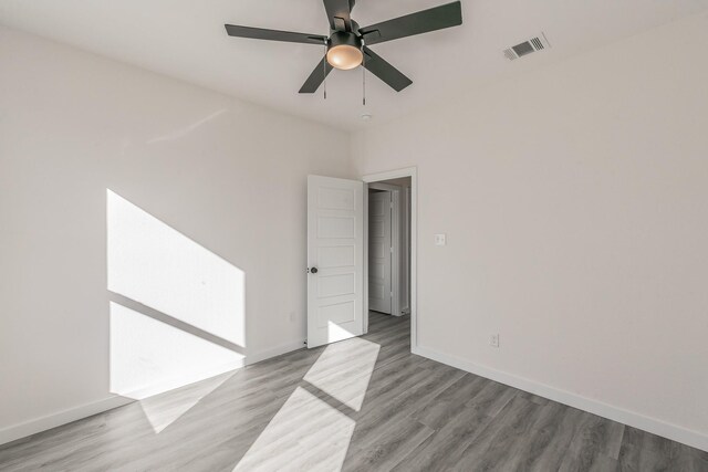 empty room with baseboards, visible vents, ceiling fan, and wood finished floors