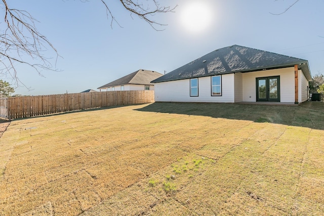 back of house featuring a yard, a shingled roof, fence, and french doors