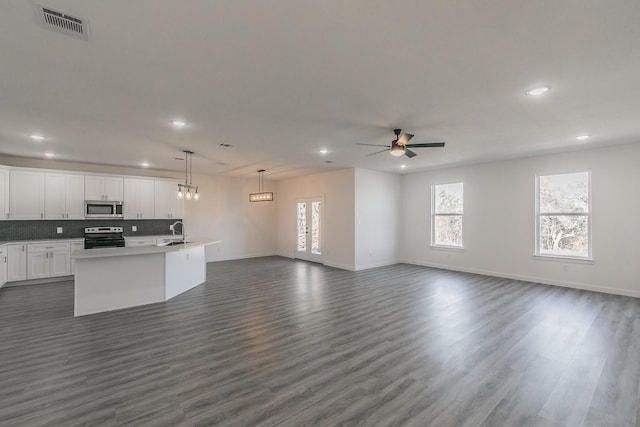 kitchen with visible vents, appliances with stainless steel finishes, open floor plan, white cabinets, and a sink