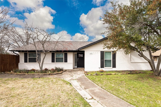 ranch-style home featuring a front yard, brick siding, fence, and roof with shingles