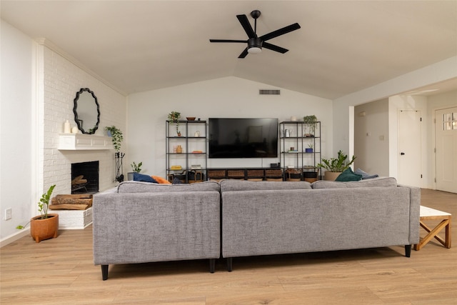 living room featuring vaulted ceiling, light wood finished floors, visible vents, and a ceiling fan