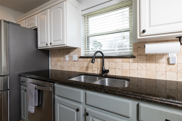 kitchen featuring tasteful backsplash, dark stone counters, a sink, and stainless steel dishwasher