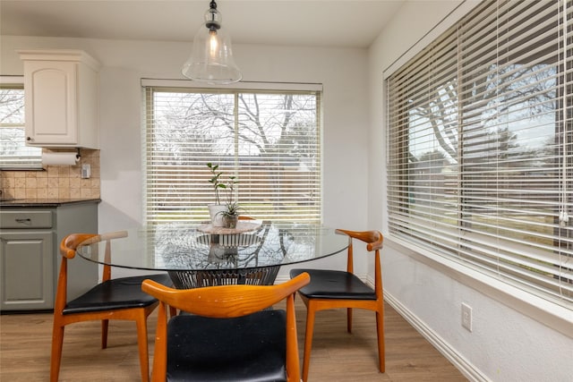 dining space with baseboards and light wood finished floors