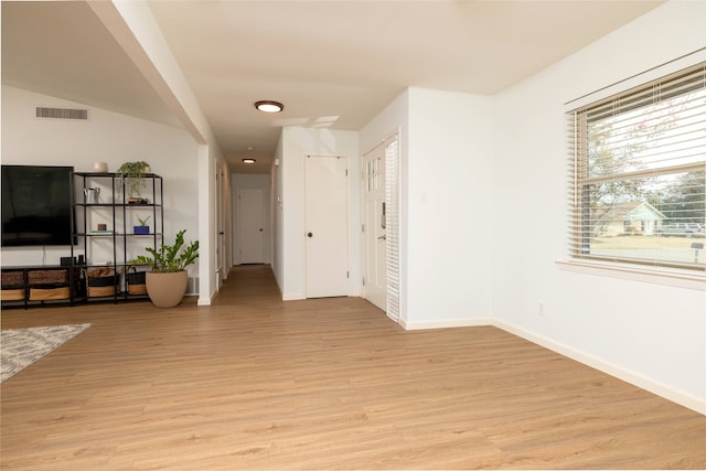 living area with light wood-type flooring, visible vents, and baseboards